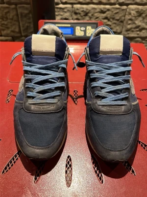 Blå Philippe Model sneakers - Snygga blå sneakers från Philippe Model med mesh och mockadetaljer. Skorna har ljusblå skosnören, beige detaljer på plösen och häl, samt en klassisk låg siluett. Perfekta för dig som gillar stilrena och sportiga sneakers. Pris kan diskuteras och de kommer tyvärr inte med någon låda 