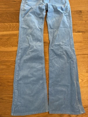 Ljusblåa utsvängda manchesterbyxor - Säljer ett par ljusblåa manchesterbyxor med utsvängda ben och klassiska fickor bak. Byxorna har hällor för skärp och är tillverkade i mjuk manchester. Perfekta för dig som gillar retrostil och vill sticka ut med färg.