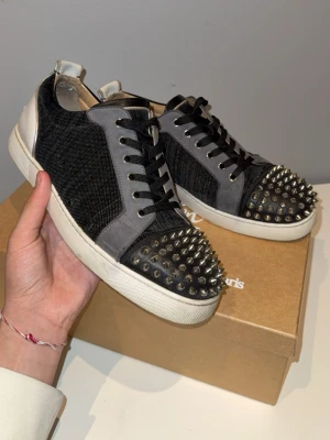 Christian Louboutin svarta sneakers -  Säljer ett par snygga Christian Louboutin skor Vid ett ganska bra pris, fem extra spikar extra snören och dust bagg medföljer kontakta mig för att justera priset