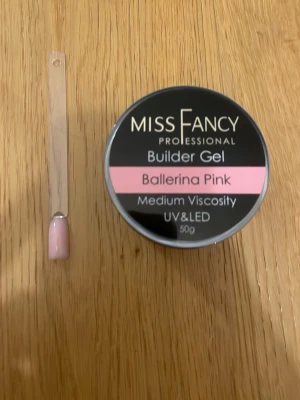 Miss Fancy Builder Gel Ballerina Pink - Byggel från Miss Fancy i färgen Ballerina Pink. Gelen har medium viskositet och används för att bygga naglar med UV eller LED-lampa. Ger en mjukt rosa, naturlig finish som passar perfekt för eleganta naglar. Förpackningen innehåller 50g.