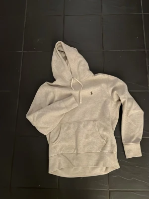 Grå hoodie från Polo Ralph Lauren - Snygg beige hoodie från Polo Ralph Lauren. Tröjan har en broderad logga på bröstet.