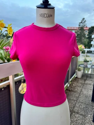 Rosa t-shirt, topp - Snygg t-shirt i stark rosa färg. Modellen är mjuk, stretchig och tight med korta ärmar och rund halsringning 💖