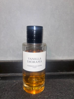 Vanilla Diorama parfym från Dior 90/100ml - Vanilla Diorama från Christian Dior är en lyxig parfym i en stilren, rund glasflaska med svart lock. Doften har en varm, gyllene färg och flaskan har en enkel vit etikett med elegant text. Perfekt för dig som gillar exklusiva och unika dofter. Köpt i Wien och kvitto box och allt finns, dock är mitt namn ingraverat på flaskan. Nästan inte andvänd