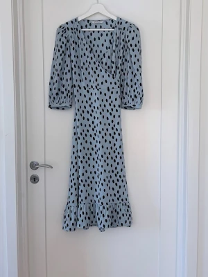 Ljusblå prickig omlottklänning - Onlys populära Olivia omlottklänning med puffärmar och volangkanter.  Ljusblå med svarta prickar. Är slutsåld!  Använd två gånger så i nyskick.  