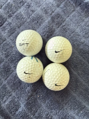 Nike vita golfbollar 4-pack - Fyra vita golfbollar från Nike med klassisk dimple-design och Nike-logga tryckt på varje boll. En av bollarna har även texten SFT. Perfekta för dig som vill fylla på golfbagen med snygga bollar från ett känt märke.