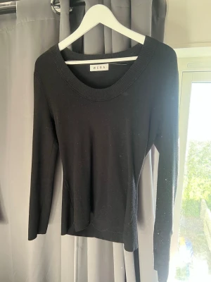 Svart stickad tröja från Wera - En stilren svart stickad tröja från Wera med rund halsringning och långa ärmar. Tröjan har en enkel, klassisk design och är perfekt att matcha med jeans eller kjol. Materialet ser mjukt och bekvämt ut, och den ribbade kanten vid halsen ger en snygg detalj.