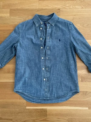 Ralph Lauren Skjorta - Jättefin och snygg raffe skjorta. Storlek L (14-16) i Ralph Laurens barn så passar runt 155-170 beroende på hur man vill att den ska sitta! Riktigt skön och as go till sommaren. Säljer då den inte passar längre, priset går att diskuteras vid bra affär!😊
