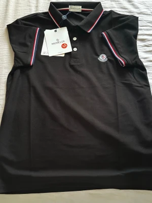 Svart pikétröja med logga - Använt 1 gång, väldigt VÄLDIGT BRA skick och skönt att ha på sig