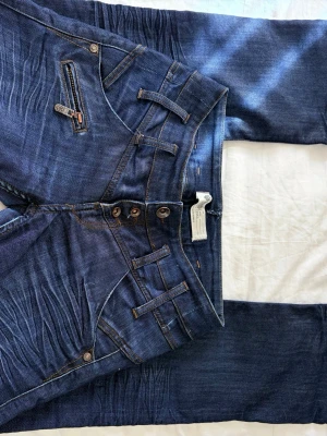 Lågmidjade jeans med detaljer - Lågmidjade bootcut jeans från Freeman T Porter I fint skick och knappt använda, lite omsydda baktill men inget som syns vid användning eller känns av alls  Midja tvärs över: 38 cm Innerbenslängd: 80 cm