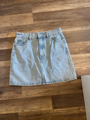 Ljusblå denimkjol från SHEIN - Ljusblå denimkjol från SHEIN med klassisk femficksdesign och bälteshällor. Kjolen har en rak och kort passform med knapp och dragkedja framtill. Perfekt för dig som gillar en enkel och tidlös look. Jag skulle säga medelhög midja. 