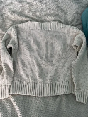 Beige stickad tröja med ribbade detaljer - Säljer en enkel och stilren beige stickad tröja med ribbade muddar vid ärmslut, nederkant och hals. Tröjan har en rak passform och är långärmad, perfekt för lager på lager. Materialet känns mjukt och bekvämt.