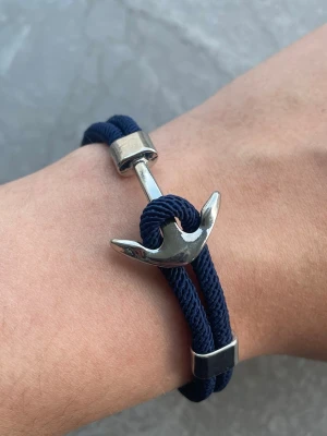 Marint armband med ankare - Snyggt armband med marinblått rep och ett silverfärgat ankare i metall som lås. Dubbel tvinnad design ger en cool och avslappnad look. Perfekt accessoar för dig som gillar nautisk stil och vill sticka ut lite extra.