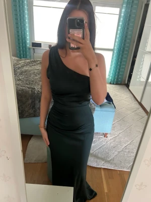 Mörkgrön oneshoulder långklänning Asos - En super fin festklänning från ASOS i grön färg, den är one shoulder och aldrig använd🌸  Storlek 32 (XXS) men passar 34 samt 36, klänningen är också väldigt långt och går ner till marken om man är 175 cm och under🤗  Skickar gärna fler bilder och svarar på frågor, pris kan diskuteras🥰