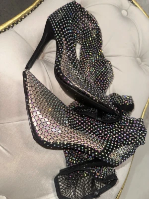 Svarta pumps med nät och strass - Unika svarta pumps med spetsig tå och hög klack, täckta av glittrande strass och fisk-nät. Perfekta för dig som vill sticka ut och älskar bling. Helt nya oanvända 