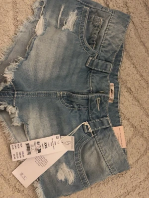 Ljusa lowwaist jeansshorts - Säljer ett par helt nya ljusblå jeansshorts från Gina tricot. Lite stora i storleken.