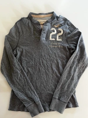 Hollister California Henley tröja  - Riktigt snygg Hollister California henley tröja i grå färg. Fint skick inga fel storlek L kan ta mått vid behov. Pris endast 389kr kom gärna med prisförslag och frågor har även mer i profilen rabatt vid flera följ gärna 😁