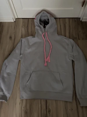 Syna world tracksuit - Grå rosa syna world tracksuit som är helt ny med prislappar! Går att köpa styckvis också. Hör av dig om du vill köpa endast hoodien eller byxorna så diskuterar vi ett pris!