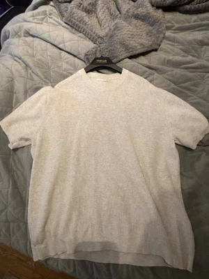 Ljusgrå ribbad topp  - Säljer en ljusgrå ribbad topp från Zara med korta ärmar och rund hals. Toppen har en enkel och clean design som passar perfekt till många olika stilar. Materialet känns mjukt och bekvämt mot huden. Perfekt nu för fina sommarkvällar☀️