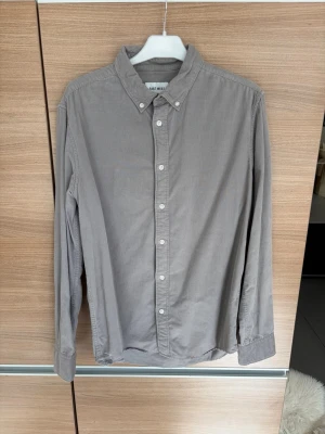 Grå manchesterskjorta från East West - Snygg grå skjorta i manchester från East West. Skjortan har klassisk krage med knappar, långa ärmar och vita knappar framtill. Perfekt för dig som gillar en stilren och enkel look med lite struktur i materialet.