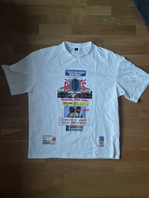 Vit t-shirt med färgglatt tryck - Vit t-shirt med stort, färgglatt tryck på framsidan med text och grafik inspirerat av boxning och sport. Klassisk passform och rund hals. Perfekt för dig som gillar statement-plagg och sportiga vibbar.