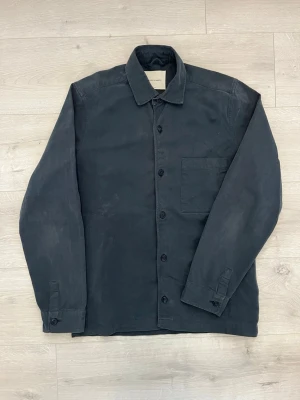 Overshirt mörkblå - Säljer en stilren mörkblå overshirt från A Day’s March. Perfekt som ett extra lager under vår, sommar och tidig höst.  • Färg: Mörkblå • Skick: Fint skick • Använd under en vårsäsong • Tidlös och minimalistisk design • Perfekt att bära över t-shirt, skjorta eller tunn stickad tröja • Passar lika bra till jeans som chinos