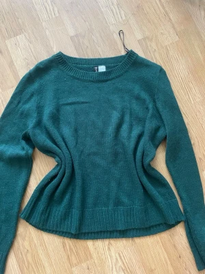 Mörkgrön stickad tröja H&M - Mysig mörkgrön stickad tröja från H&M med rund halsringning och långa ärmar. Tröjan har ribbade muddar vid ärmslut och nederkant❤️