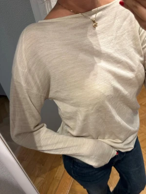 Beige långärmad tröja i bomull - En stilren beige långärmad tröja med avslappnad passform och rundad halsringning. Tillverkad i mjukt och tunt bomullsmaterial som känns skönt mot huden. Bra kvalitet, fint material, aldrig använd därav inga noppror osv. Inköpspris: 599kr