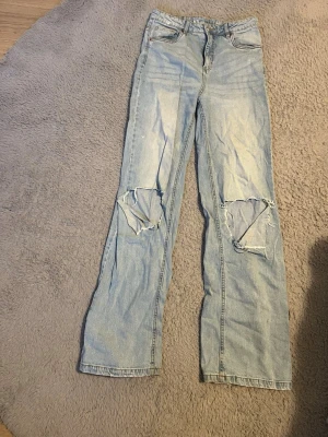 Ljusblå slitna jeans med hål - Baggy jeans med hål på knäna. Storlek 170 men passar xs