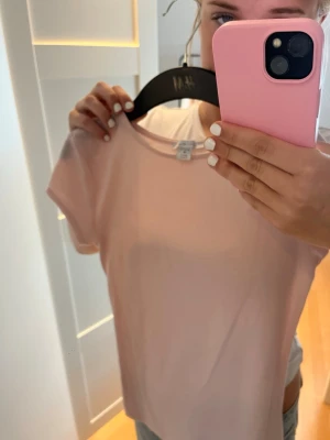 Ljusrosa basic t-shirt från Newyorker - En enkel och stilren ljusrosa t-shirt från H&M. T-shirten har rund halsringning och korta ärmar, perfekt till jeans eller kjol. Tillverkad i mjuk bomull för en skön känsla hela dagen.