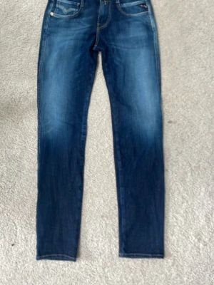 Blå skinny jeans från Replay - Snygga blå skinny jeans från Replay med klassisk femficksmodell och diskreta slitningar. Jeansen har en mörk tvätt med ljusare partier och detaljerade sömmar på bakfickan. Tillverkade i stretchigt denim för skön passform.