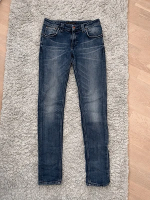 Blå slim fit jeans från Nudie Jeans - Säljer ett par blå slim fit jeans från Nudie. De är i modellen skinny lin, en slimfit modell. Nypris: ca 2000kr. De har otroligt snygga fades som verkligen får dem att sticka ut ur mängden🤩
