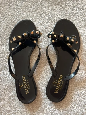 Svarta sandaler med nitar från Valentino - Coola svarta sandaler från Valentino Garavani med dekorativa nitar och en snygg rosett på remmen. Oridinare pris på hemsidan: 3900 kr. 