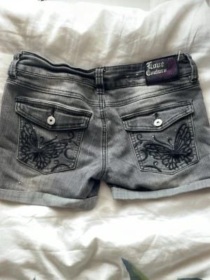 Grå Love Couture shorts med fjärilar - Säljer ett par grå denimshorts från Love Couture(Kappahl) med snygga broderade fjärilar på bakfickorna och dubbla knappar fram. Om du har frågor om shortsen är det bara att du skriver! Samt om du vill se mina försäljnings omdömen är mitt vinted användarnamn Irene10rs. Priset går självklart att diskutera!💝💝