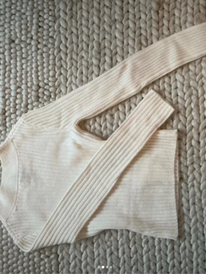 Vit ribbstickad tröja - Säljer en vit ribbstickad tröja med lång ärm och rund hals. Tröjan har en smal passform och är tillverkad i ett mjukt, stretchigt material som känns skönt mot huden. Perfekt att styla med jeans eller kjol.