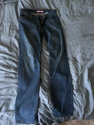 Blå slim fit jeans 32x34 - Slim fit jeans i klassisk blå denim med raka ben och snygga detaljer. Jeansen har fem fickor och kontrastsömmar. Perfekt för dig som gillar en stilren och enkel look. Materialet är bomullsdenim.