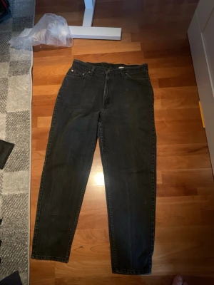 Svarta Levi's jeans - Säljer ett par svarta Levi's jeans med raka ben. Klassisk femficksmodell med knapp och dragkedja framtill. Jeansen har en avslappnad passform och är tillverkade i kraftig denim. Perfekta för en cool och avslappnad stil.