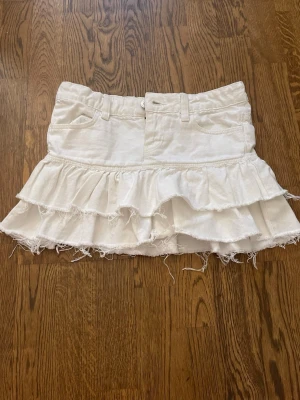 Vit volangkjol med råa kanter - Vit volang kjol från Gina tricot. Är i bra skick men har används mycket under förra sommaren. Säljer för den är för liten och tvättar innan jag skickar!