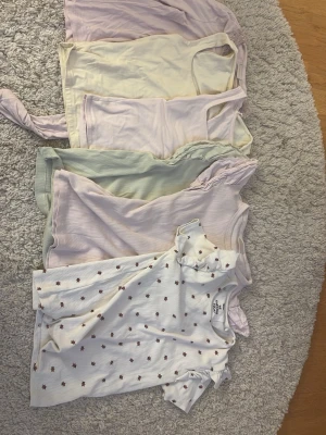 Sött topp-paket i pastell och blommigt - 6 toppar i olika pastellfärger och en vit topp med små nyckelpigor. Blandade modeller med både ärmlösa och kortärmade varianter, vissa med volangdetaljer. 5 av dem är från Gina och den vita är från WE/be awsome today. Storlekar mellan 146/152-xxs men är väldigt lika i storlek. Säljer alla i ett pack då storlekarna är jämna.
