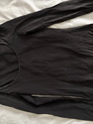 Svart långärmad topp från Vero Moda - En basic svart långärmad topp från Vero Moda i mjukt och stretchigt material. Rund halsringning och figurnära passform gör den enkel att styla till olika looks. Perfekt som lager-på-lager-plagg eller för en clean och enkel stil. Säljer även den vita, endast som bild för att visa passformen ☺️