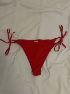 Röda bikiniunderdelar med knyt - Snygga röda bikiniunderdelar med knyt i sidorna. Klassisk trekantsmodell från Lager 157 i stlk M.    !! TVÄTTAS INNAN JAG SKICKAR !!