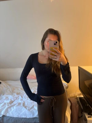 Mörkblå långärmad topp med fyrkantig ringning - Snygg mörkblå långärmad topp med fyrkantig ringning och figurnära passform. Perfekt att styla med jeans eller kjol för en trendig look. Enkel och stilren design som passar till många outfits.