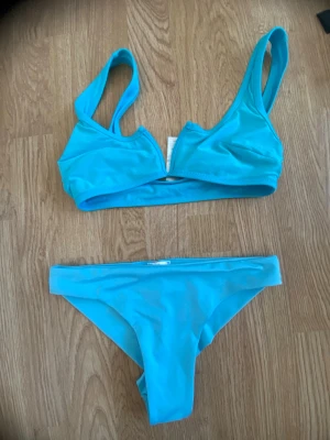 Turkos bikini med sportig topp - Snygg turkos bikini med enkel, sportig topp och matchande trosor. Aldrig använd Båda delarna har en stilren design utan mönster eller extra detaljer. Perfekt för strand eller poolhäng i sommar.