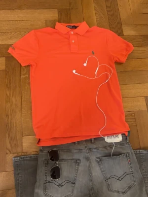 Pikétröja från Ralph Lauren - Grym kvalité, inga defekter. Storlek S, sitter bra vid axlarna och slutar vid midjan. Bilderna kan va missledande, men den är koral färgad.              Mått -|-  Axelmått: 42 cm  Längd: 64 cm.       Bröst: 46 cm                                                    Leverans sker dagen efter, har du nån fråga är det bara att skriva:)