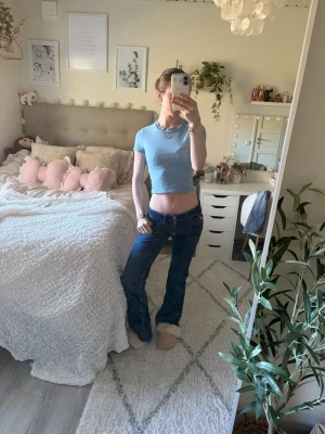 Mörkblå bootcut jeans med låg midja - Säljer ett par mörkblå bootcut jeans med låg midja och vita kontrastsömmar. Jeansen har klassisk femficksdesign och är tillverkade i denim med lätt stretch. 