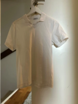 Vit piké  - Klassisk vit piké från MQ  och krage. Piken  är enkel och stilren, perfekt för en clean look. Tillverkad i bomull för en skön känsla och bra passform.