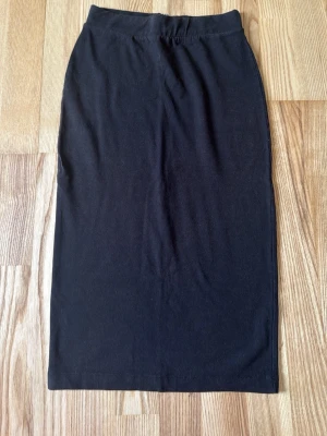Svart långkjol  - En stilren svart långkjol i mjukt material . Kjolen har en rak passform och resår i midjan för extra komfort. Perfekt att matcha med en enkel topp eller hoodie för en avslappnad look.