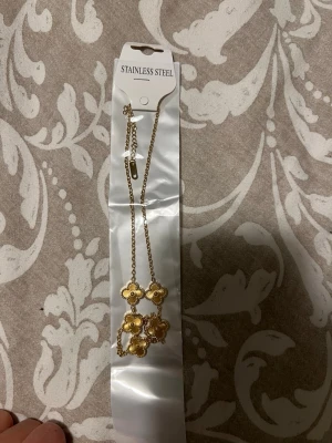 Guldfärgat halsband med blommor - Snyggt halsband i guldfärgad stainless steel med fyra blommor som hängsmycken. Kedjan är tunn och elegant, och blommorna har små detaljer som ger ett lyxigt intryck. Perfekt accessoar för att lyfta din outfit.