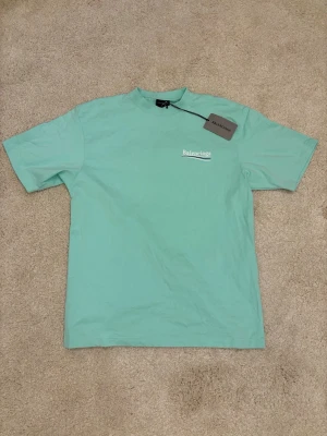 Mintgrön Balnciaga t-shirt - Fräsch mintgrön t-shirt från Balnciaga med vit logga tryckt på bröstet och ryggen. Storlek XS men sitter baggy och oversized så storlek S-M rekommenderas!