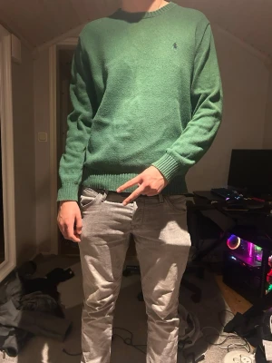 Grön stickad tröja från Ralph Lauren - Snygg grön stickad tröja från Ralph Lauren med klassisk rund halsringning och broderad logga på bröstet. Tröjan har ribbade muddar vid ärmslut och nederkant. Storlek M bra skick inte andvänd eller tvättad många gånger. PRISET DISKUTERBART