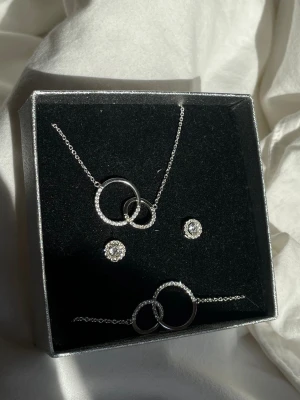 Äkta silver smycken från Mood  - Halsband, armband och örhängen i rhodinerat äkta silver med kubisk zirkonia från Mood.  Halsband mått: 42,0+3,0 cm Armband mått:  17,0+3,0 cm ursprungspris: 1300 kr 